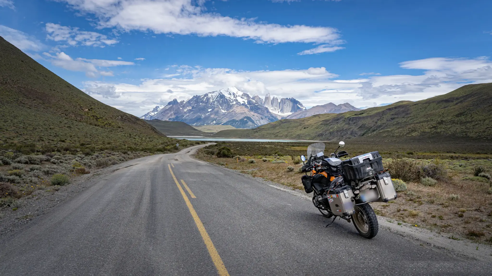 A loaded adventure motorcycle on an empty road toward Torres del Paine